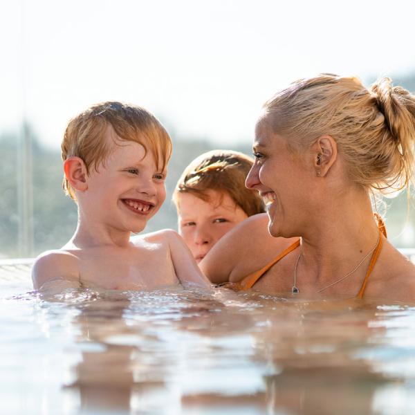 Mother and sons enjoy the outdoor hot tub in Fredericia Idrætscenter. There is a view of the entire Madsbyparken.