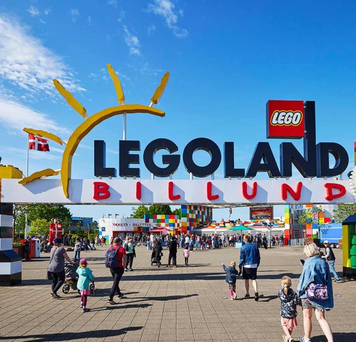 The gateway to LEGOLAND with the two LEGO® brick towers. A crowd of visitors coming to enjoy the park on a summer's day under a blue sky.